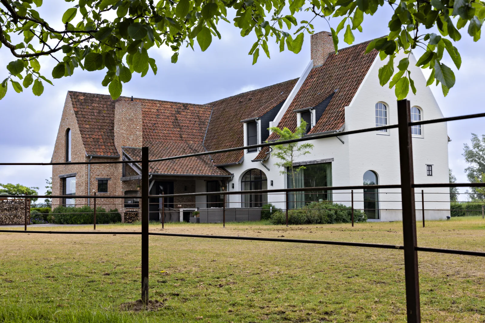 Landelijke villa in baksteen en wit, gezien vanuit het omliggende landschap
