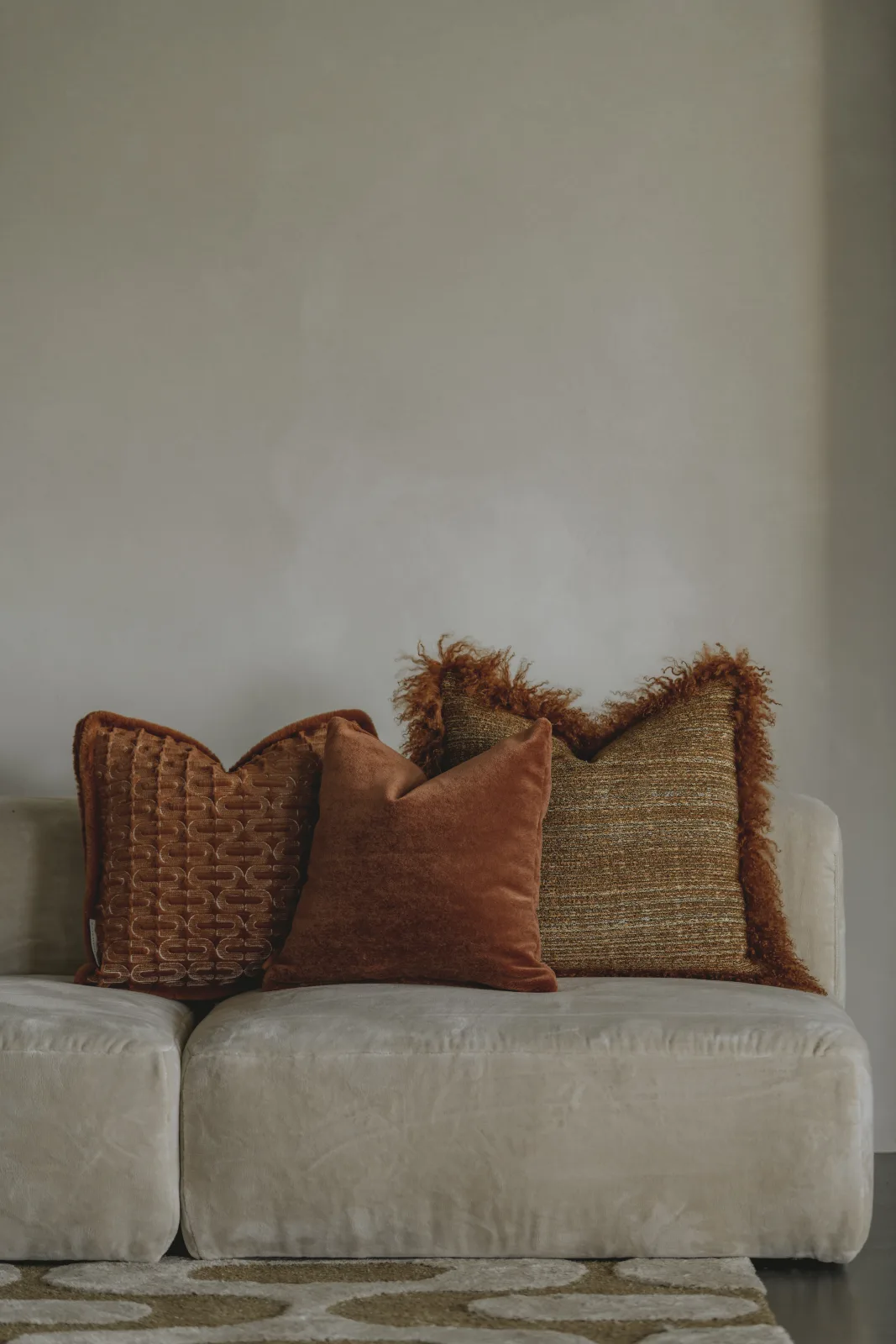 Kussens in terracotta en beige op een lichte zetel