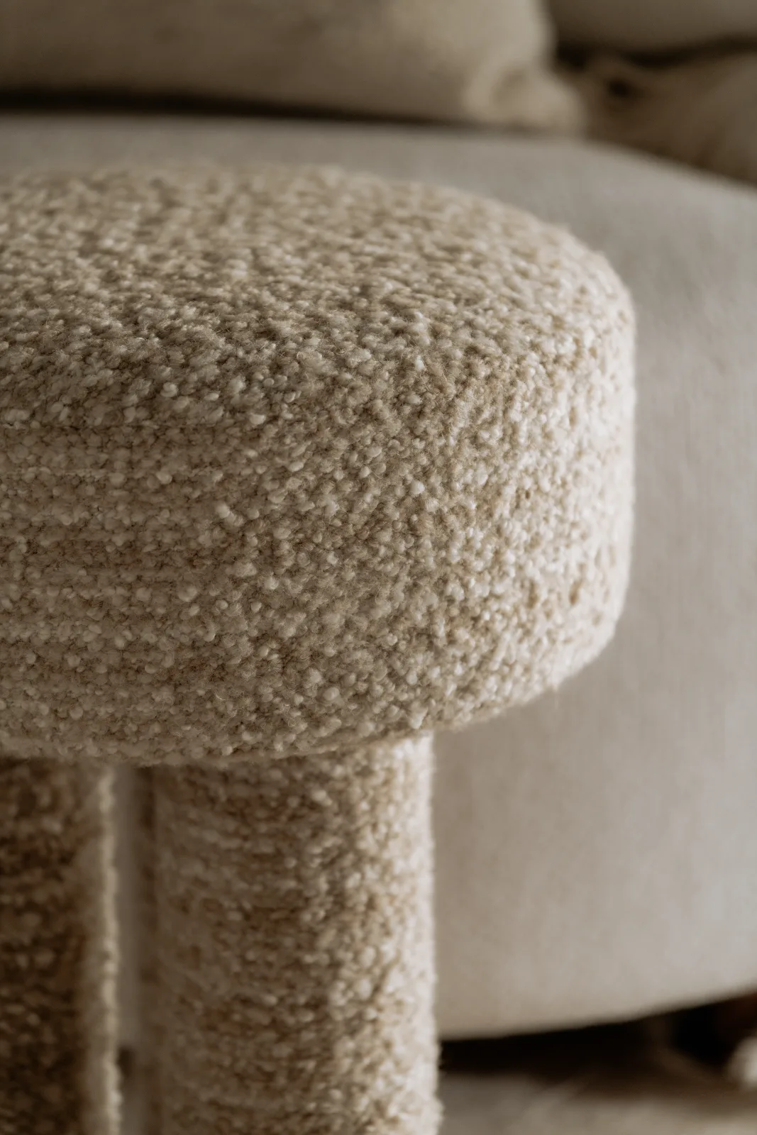 Detail van een bouclé poef in gebroken wit
