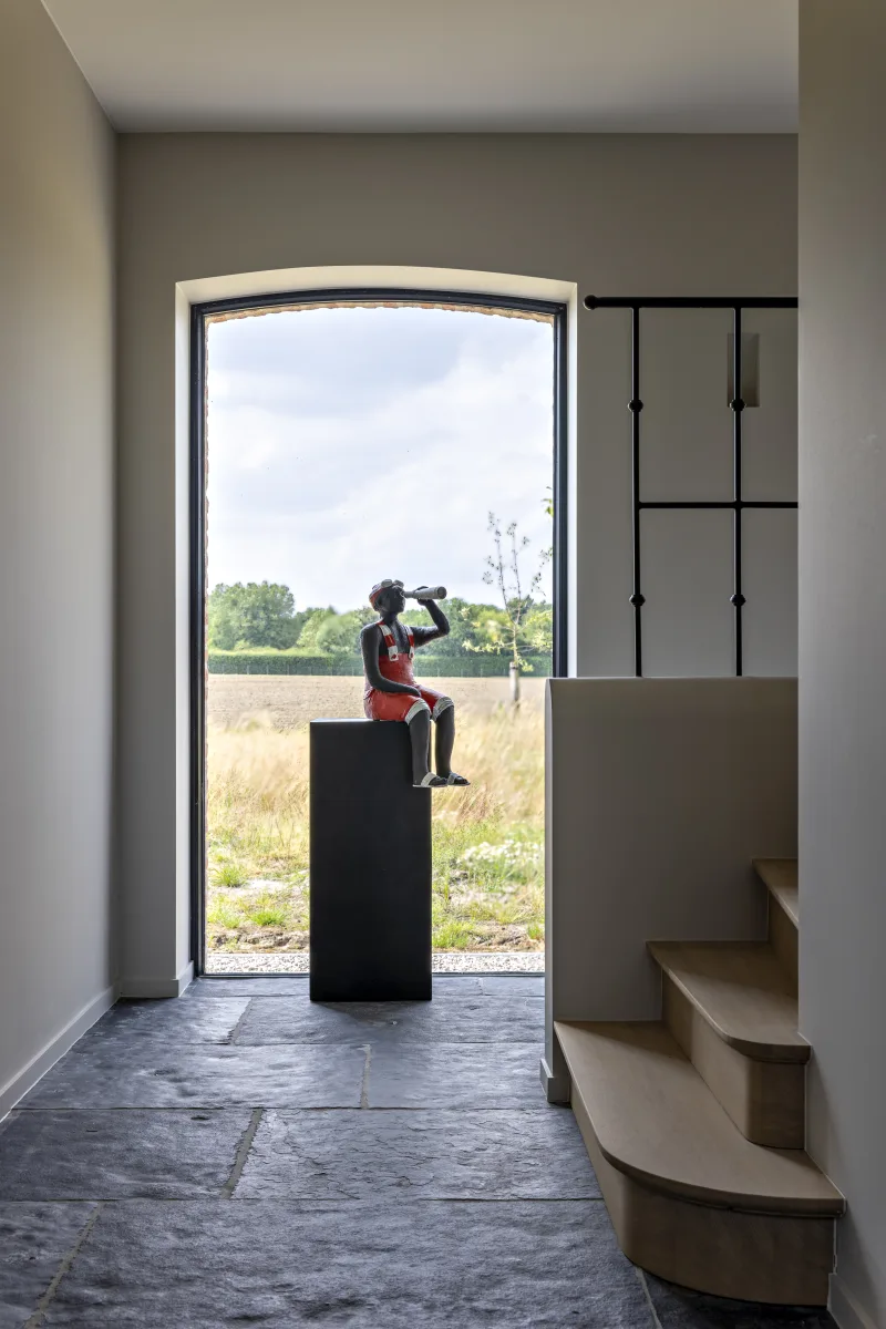 Traphal met eikenhouten trap en smeedijzeren reling, met kunstwerk