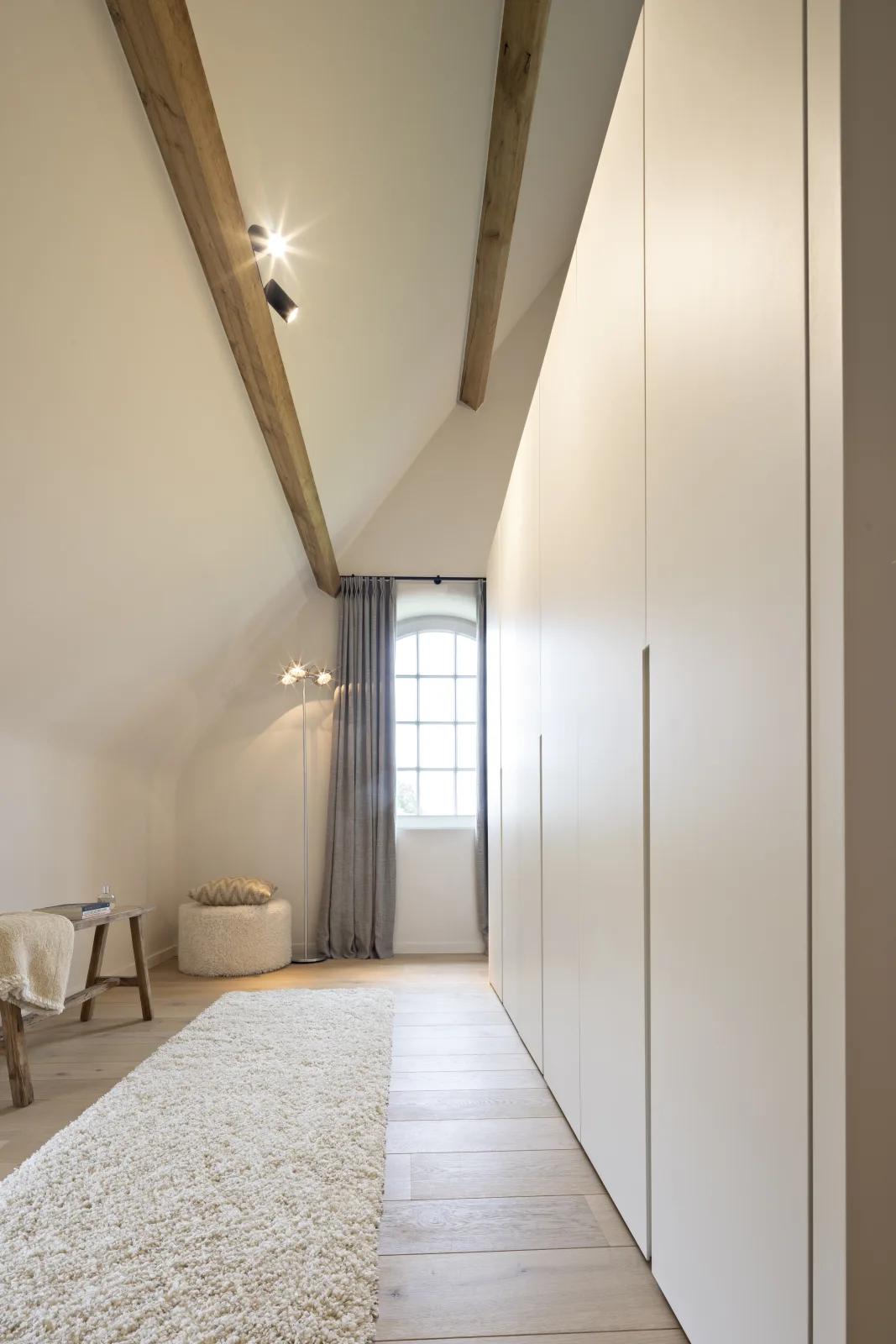 Dressing met witte maatkasten onder een schuin dak